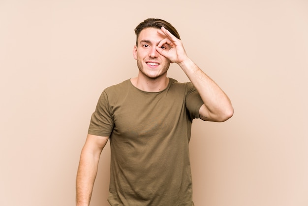 Young caucasian man posing isolated excited keeping ok gesture on eye.
