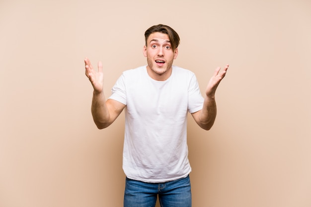 Young caucasian man posing isolated receiving a pleasant surprise, excited and raising hands.