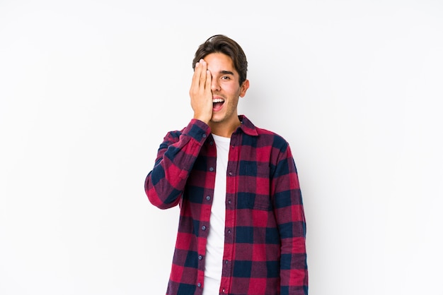 Young caucasian man posing in a pink wall having fun covering half of face with palm.