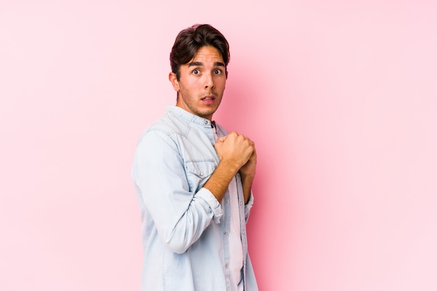 Young caucasian man posing in a pink wall isolated scared and afraid.