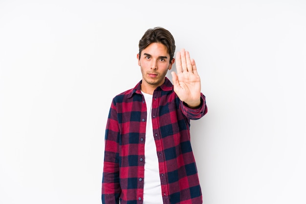 Young caucasian man posing in a pink wall isolated standing with outstretched hand showing stop sign, preventing you.