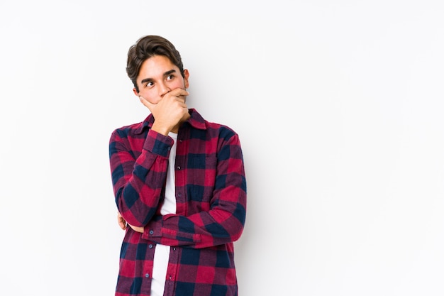 Young caucasian man posing in a pink wall isolated thoughtful looking to a copy space covering mouth with hand.