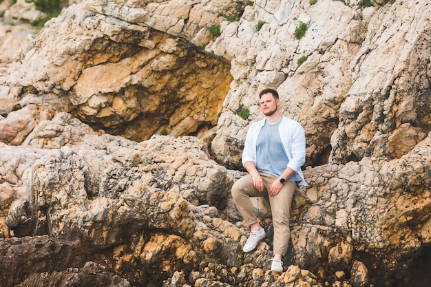 Young caucasian man posing at rocky cliff