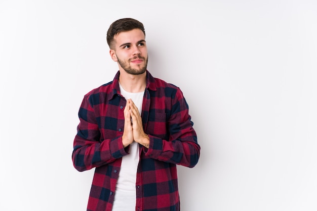 Young caucasian man posing in a white wall isolated making up plan in mind, setting up an idea.