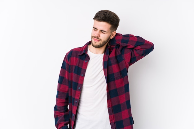 Young caucasian man posing in a white wall isolated suffering neck pain due to sedentary lifestyle.