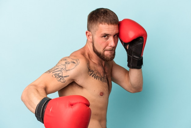 Young caucasian man practicing boxing isolated on blue background