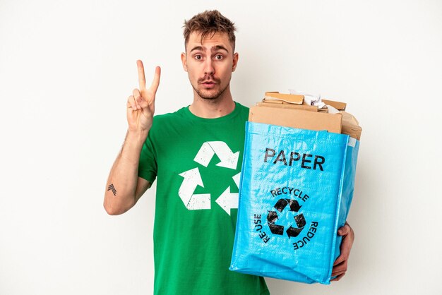 Young caucasian man recycled paper isolated on white background showing number two with fingers.