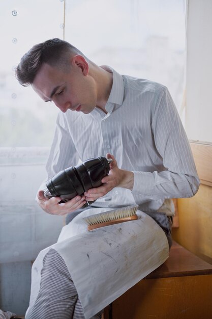 Young caucasian man repairing old male leather shoes.