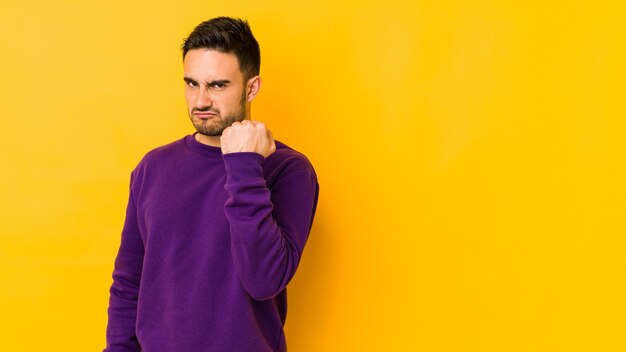 Young caucasian man showing fist, aggressive facial expression.