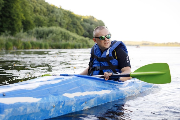 A young Caucasian man sits in a kayak and paddles The concept of water entertainment