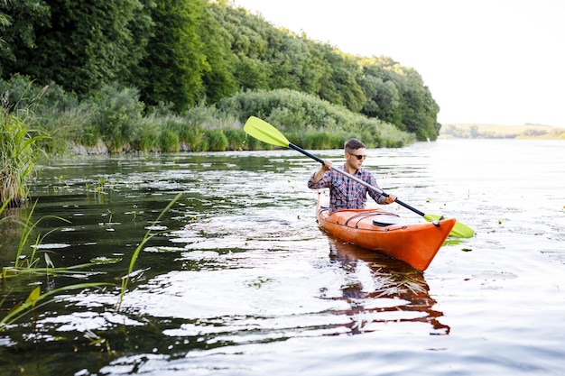 A young Caucasian man sits in a kayak and paddles The concept of water entertainment