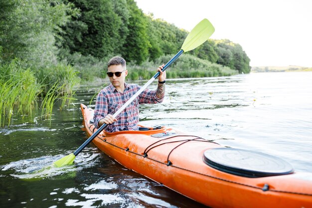 A young Caucasian man sits in a kayak and paddles The concept of water entertainment