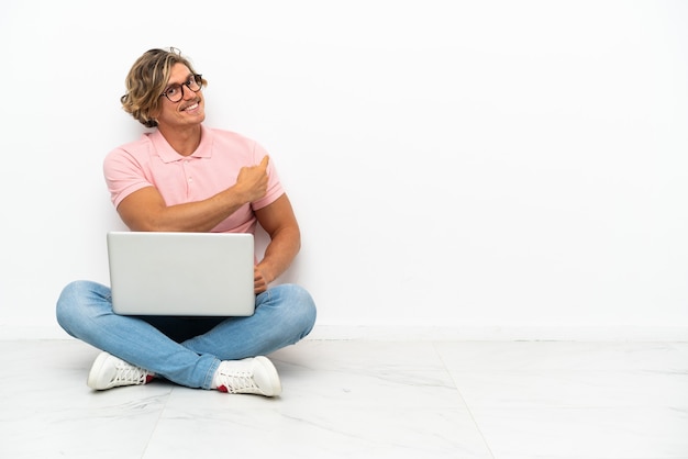 Foto giovane uomo caucasico seduto sul pavimento con il suo laptop isolato