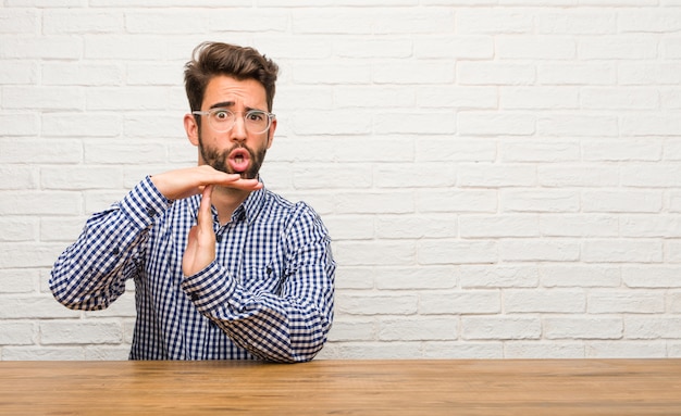 Giovane uomo caucasico seduto stanco e annoiato, facendo un gesto di timeout