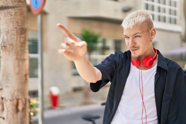 Young caucasian man smiling confident pointing with finger at street