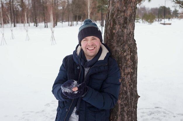 雪の冬の日に屋外に立っている若い白人男性