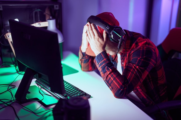 Young caucasian man streamer stressed using computer at gaming room