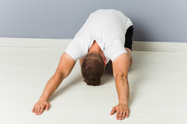 Young caucasian man stretching practicing yoga.