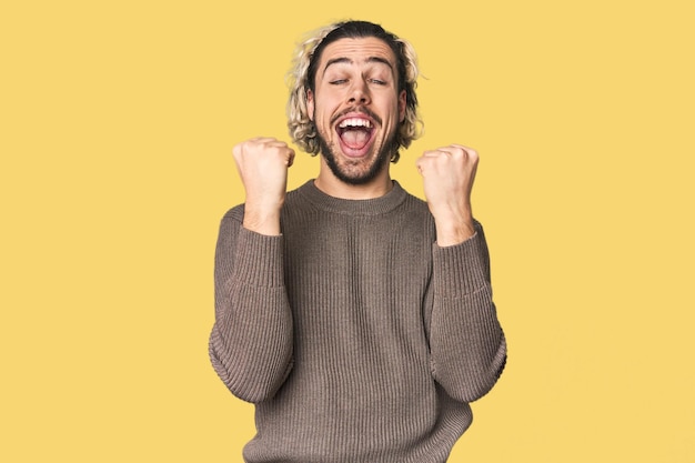 Young Caucasian man in studio setting cheering carefree and excited Victory concept