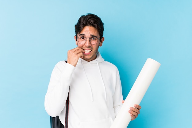 Young caucasian man studying architecture isolated biting fingernails, nervous and very anxious.