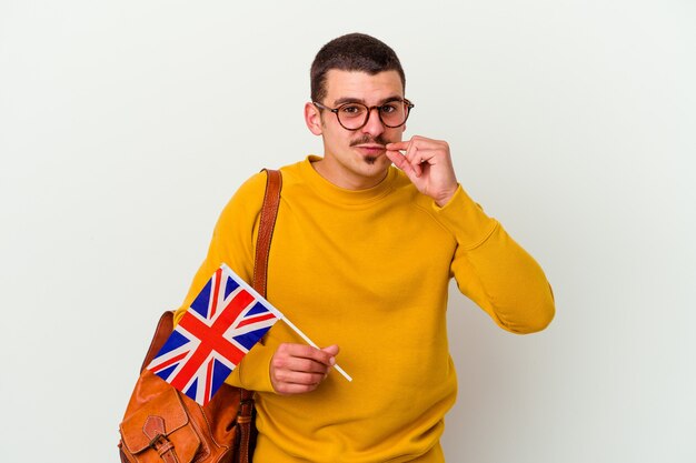 Young caucasian man studying English on white with fingers on lips keeping a secret.