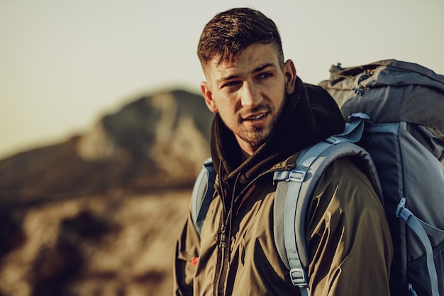 Young caucasian man traveler with big backpack hiking in the mountains