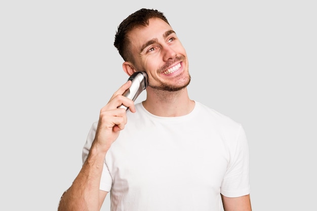 Young caucasian man using an electric shaver isolated cut out