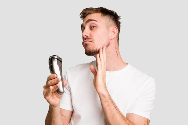 Young caucasian man using an electric shaver isolated cut out