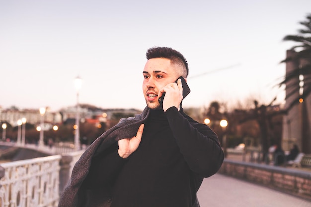 Young caucasian man using a smartphone at DonostiaSan Sebastian sea walk during sunset time