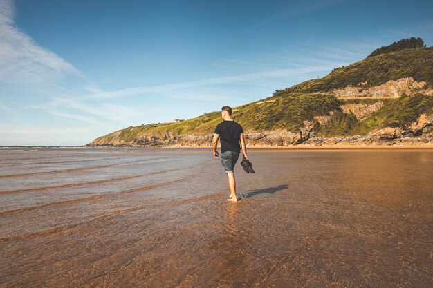 Young caucasian man walking at the beach