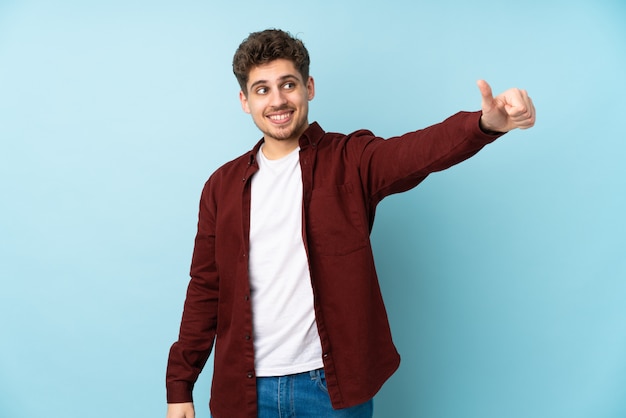 Young caucasian man wall giving a thumbs up gesture