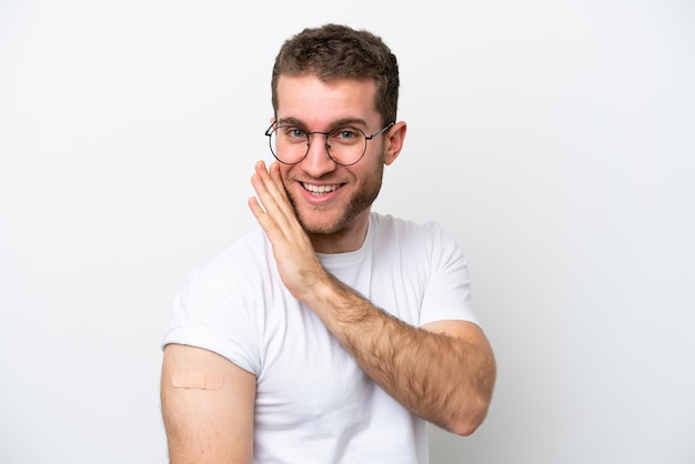 Young caucasian man wearing band aids isolated on white background whispering something