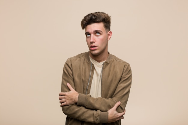 Young caucasian man wearing a brown jacket tired of a repetitive task.