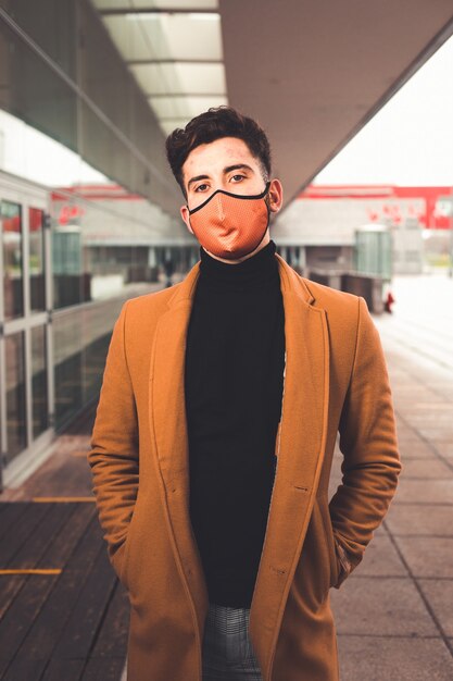 Young caucasian man wearing a brown mask with a brown coat at the street