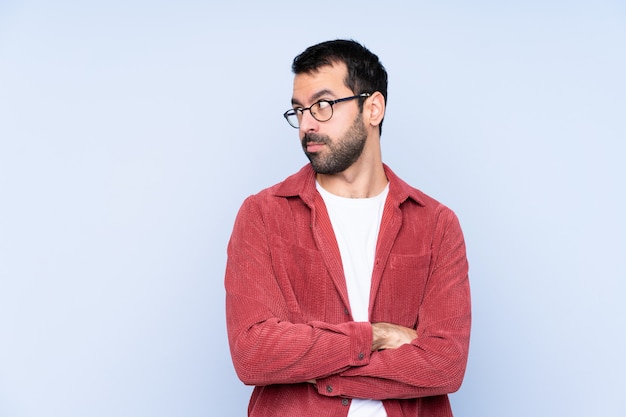 Young caucasian man wearing corduroy jacket over blue wall portrait