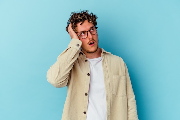 Young caucasian man wearing eyeglasses isolated on blue wall being shocked, she has remembered important meeting.