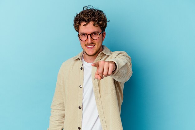 Young caucasian man wearing eyeglasses isolated on blue wall pointing to front with fingers.