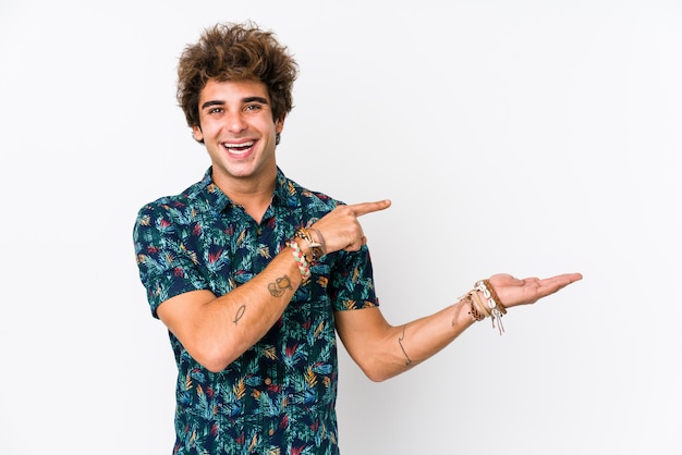 Young caucasian man wearing a flower t-shirt isolated excited holding a copy space on palm.