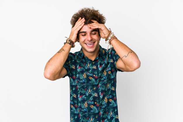 Young caucasian man wearing a flower t-shirt isolated laughs joyfully keeping hands on head. Happiness concept.