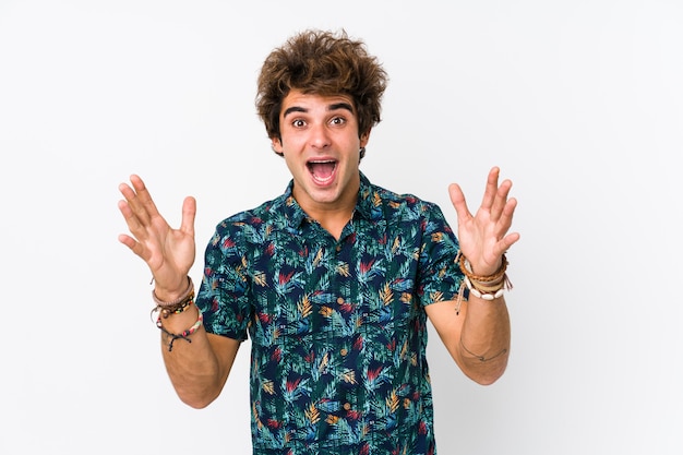 Young caucasian man wearing a flower t-shirt isolated receiving a pleasant surprise, excited and raising hands.