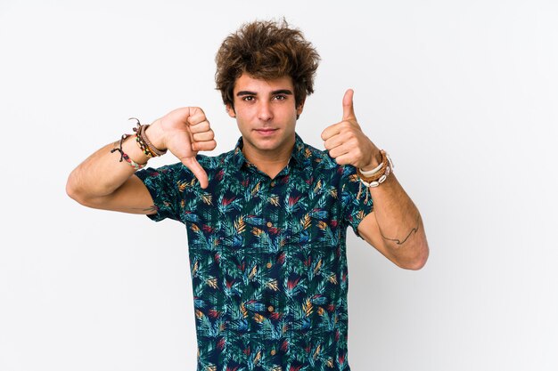 Young caucasian man wearing a flower t-shirt isolated showing thumbs up and thumbs down, difficult choose concept