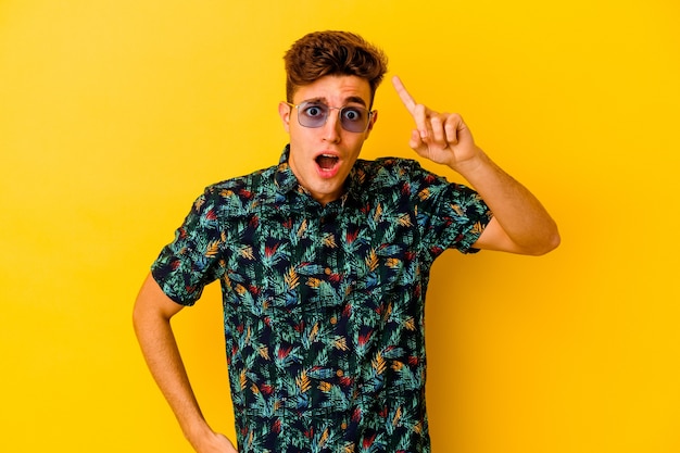 Young caucasian man wearing a Hawaiian shirt isolated on yellow background having an idea, inspiration concept.