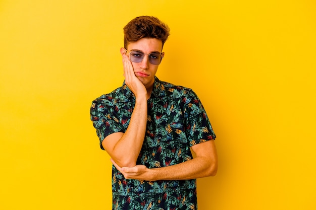 Young caucasian man wearing a Hawaiian shirt on yellow who is bored, fatigued and need a relax day.