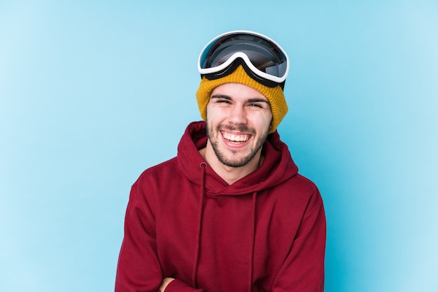 Young caucasian man wearing a ski clothes isolated laughing and having fun.