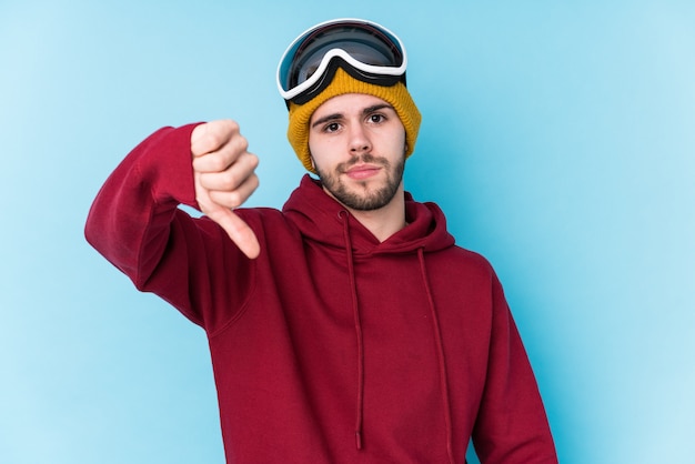 Young caucasian man wearing a ski clothes isolated showing a dislike gesture, thumbs down. Disagreement concept.