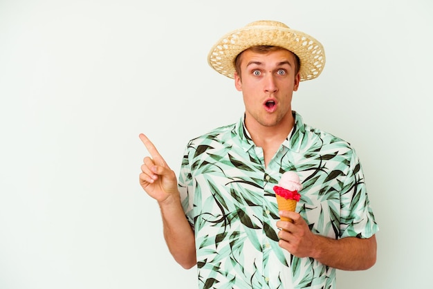 Foto giovane uomo caucasico che indossa abiti estivi e tiene un gelato isolato su sfondo bianco