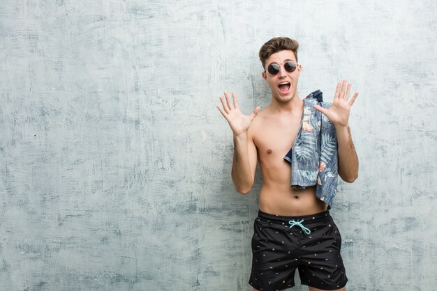 Young caucasian man wearing a swimsuit celebrating a victory or success