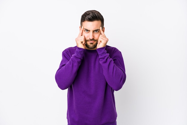 Il giovane uomo caucasico su bianco isolato si è concentrato sul compito, mantenendo gli indici che puntano la testa.