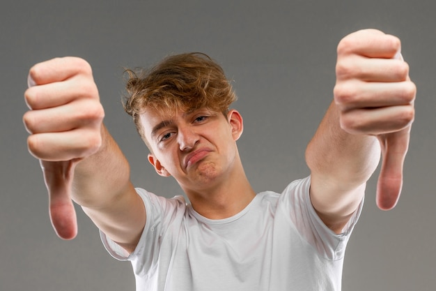 Young caucasian man in white t-shirt posing and gesticulating on camera isolated