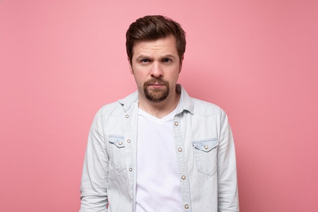 Young caucasian man with beard looking at camera without emotions